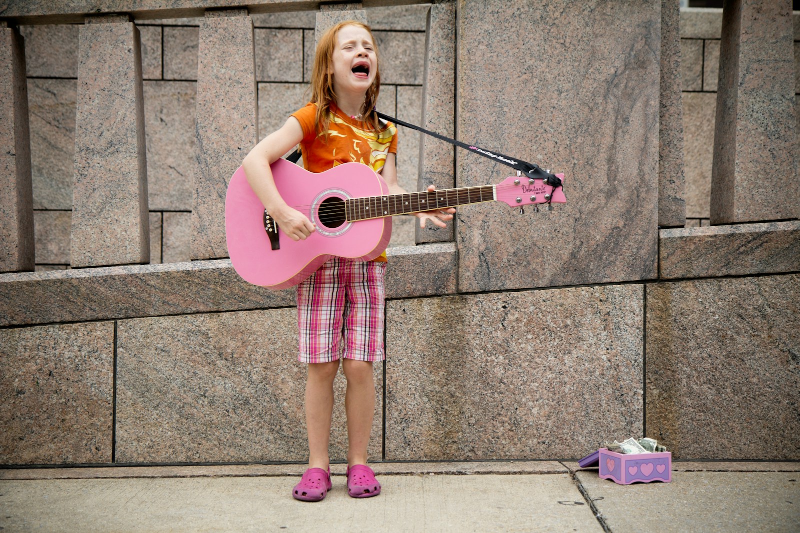 girl playing guitar near wall